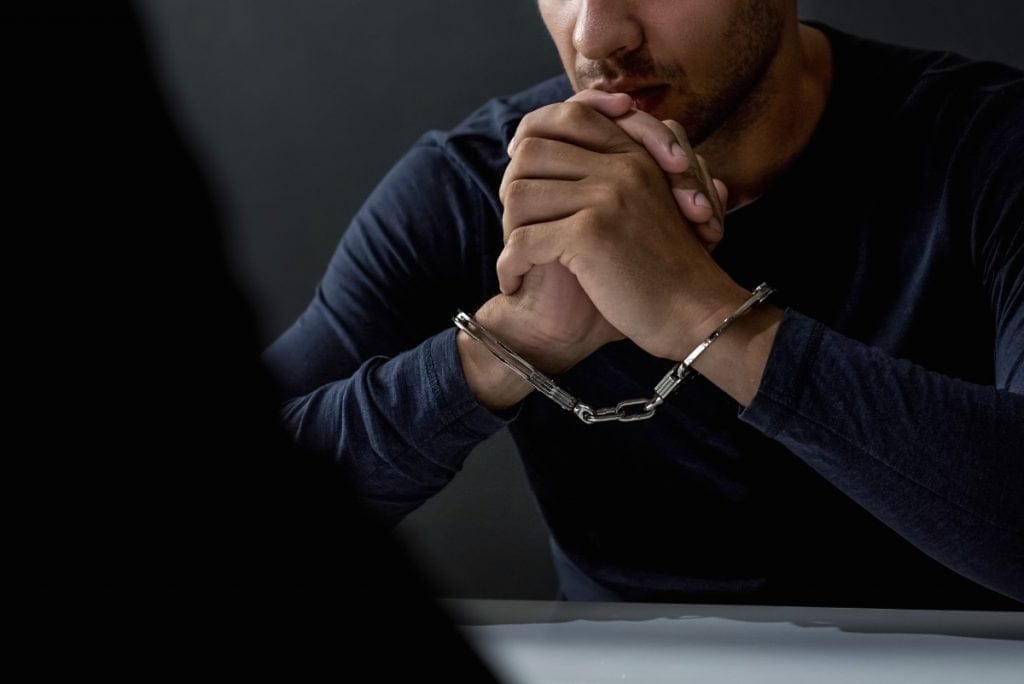 closeup of an arrested man in handcuffs